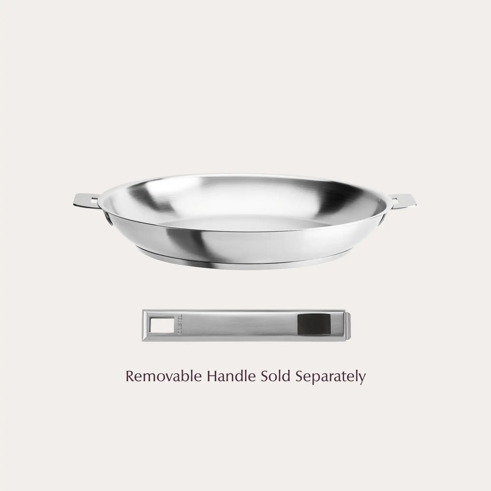 Stainless steel frying pan with short side handles and a separate removable handle below it on a light background.