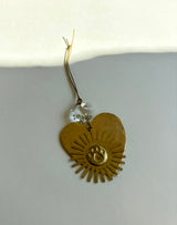Golden heart-shaped ornament with a paw print embossed in the center and sunray-like cutouts around it, hanging from a thin string with a clear faceted bead.