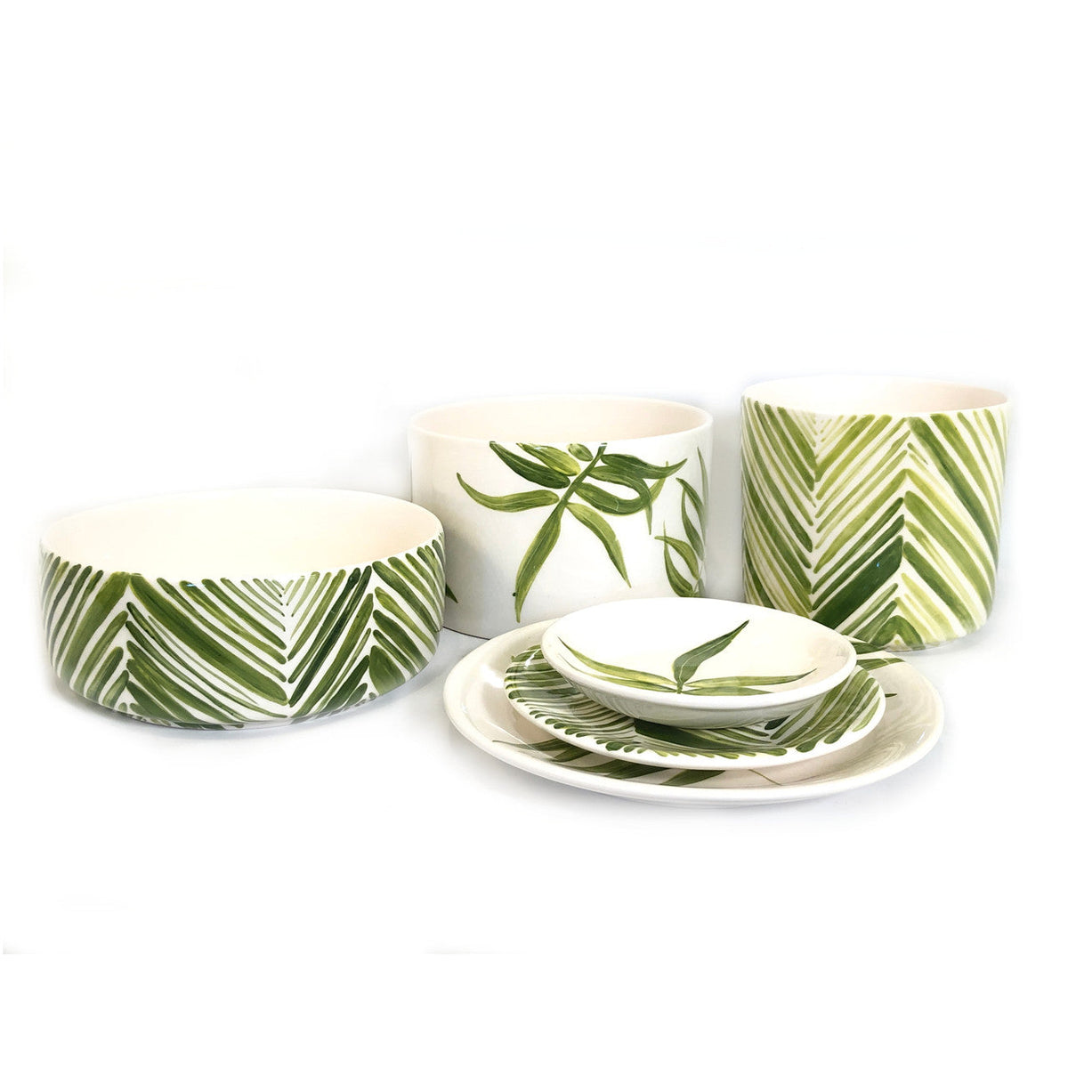 Set of ceramic bowls and plates decorated with various green palm leaf patterns on a white background, featuring wide and deep shapes.