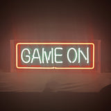 Rectangular neon sign with the phrase 'GAME ON' in white neon inside a red neon rectangular border, displayed against a dim background.