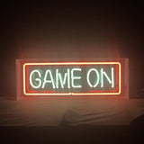 Rectangular neon sign with glowing white letters spelling 'GAME ON' surrounded by a red rectangular border, displayed against a dark background.
