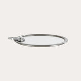 Flat glass lid made of tempered glass and stainless steel, resting on a neutral surface