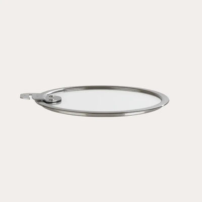 Flat glass lid made of tempered glass and stainless steel, resting on a neutral surface