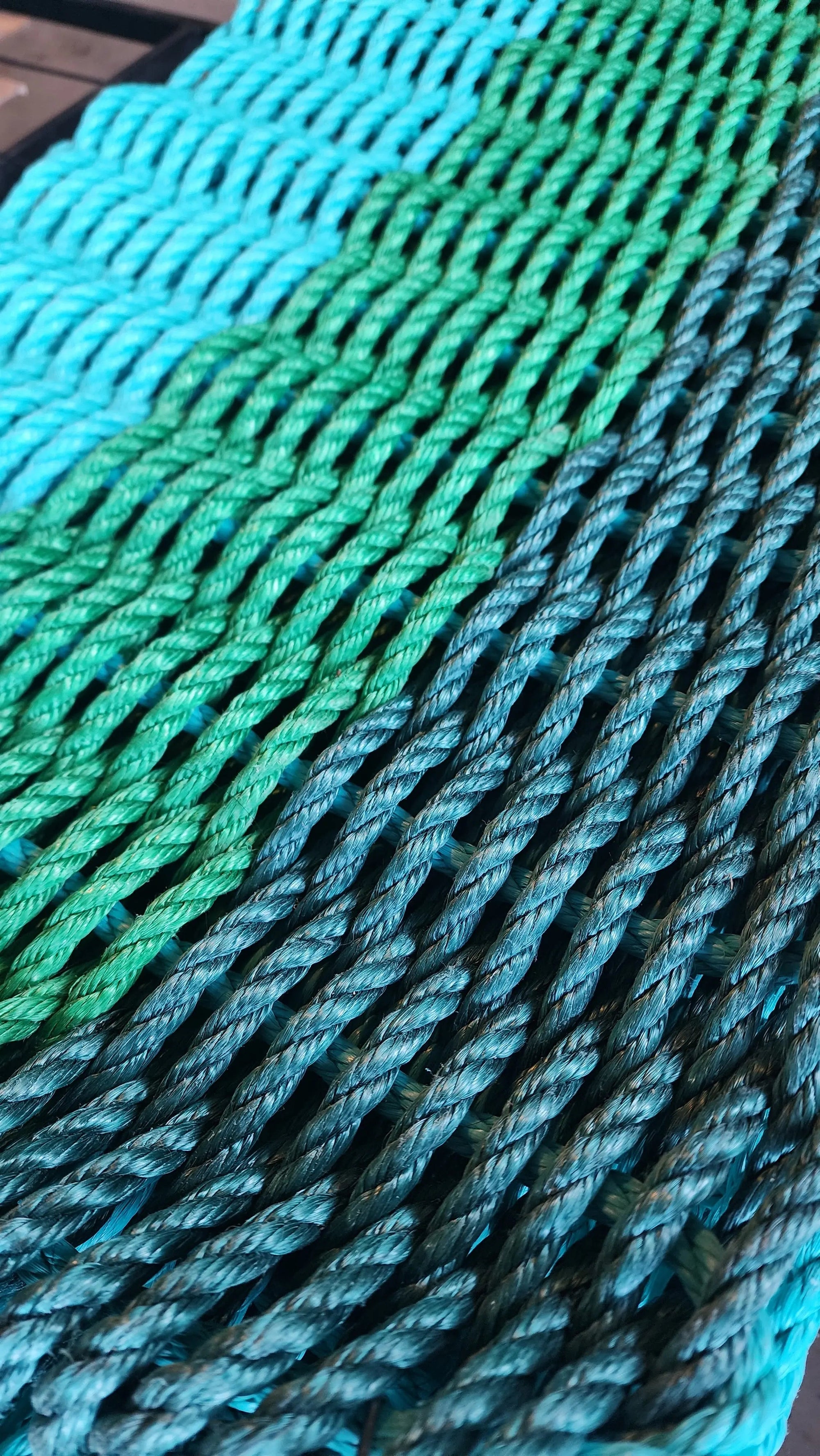 Green ombre handmade rope mat made with lobster rope in hunter green, green, and teal colors
