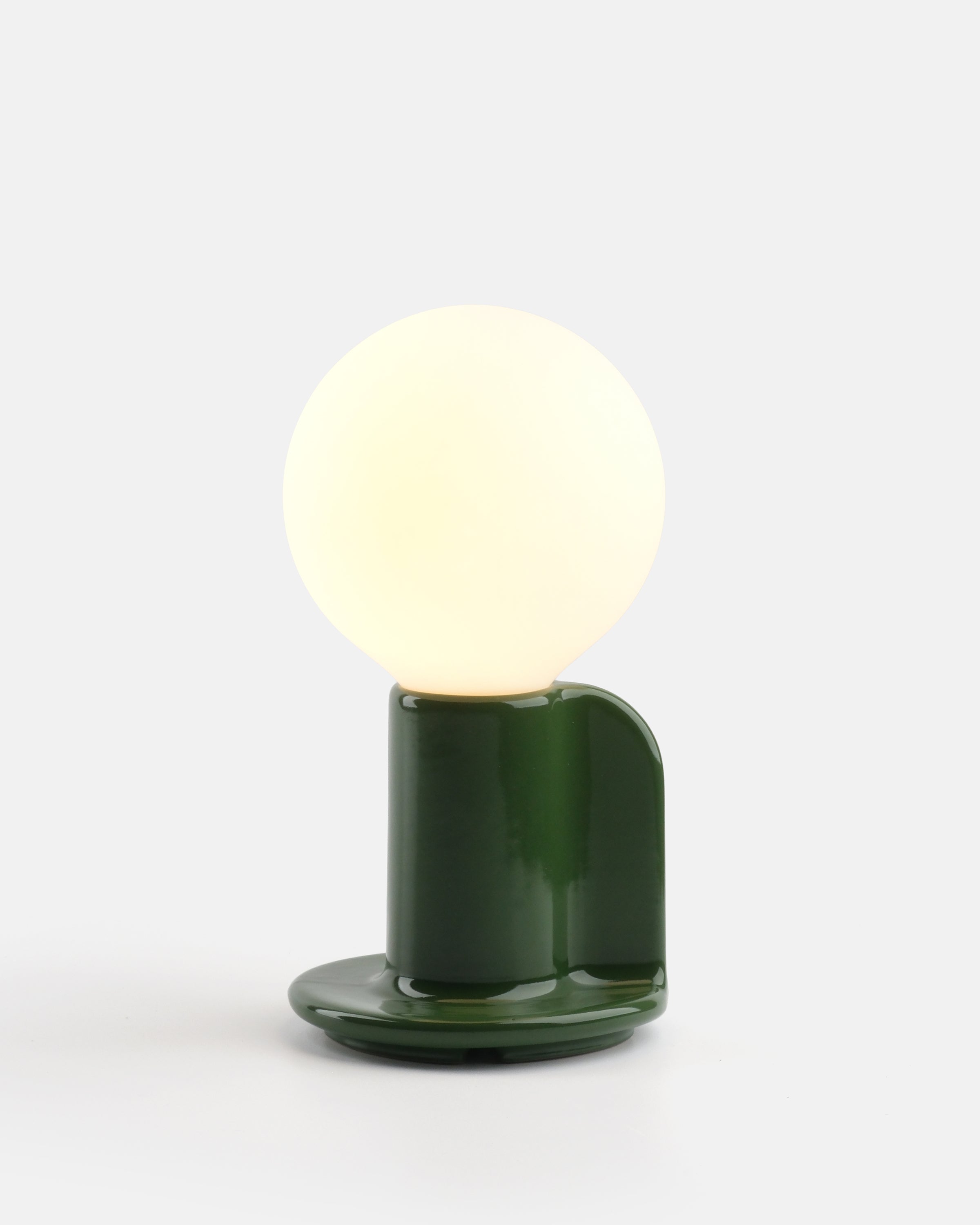 Q Lamp in green stoneware with fabric cord and paddle handle on a white surface