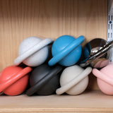 Stacked spherical planters with prominent horizontal rings in various colors including coral, speckled white, matte black, beige, blue, shiny metallic silver, and pink, displayed on a light wood shelf.