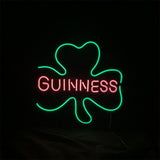Green neon outline of a three-leaf clover surrounding the pink neon word 'GUINNESS' on a black background.