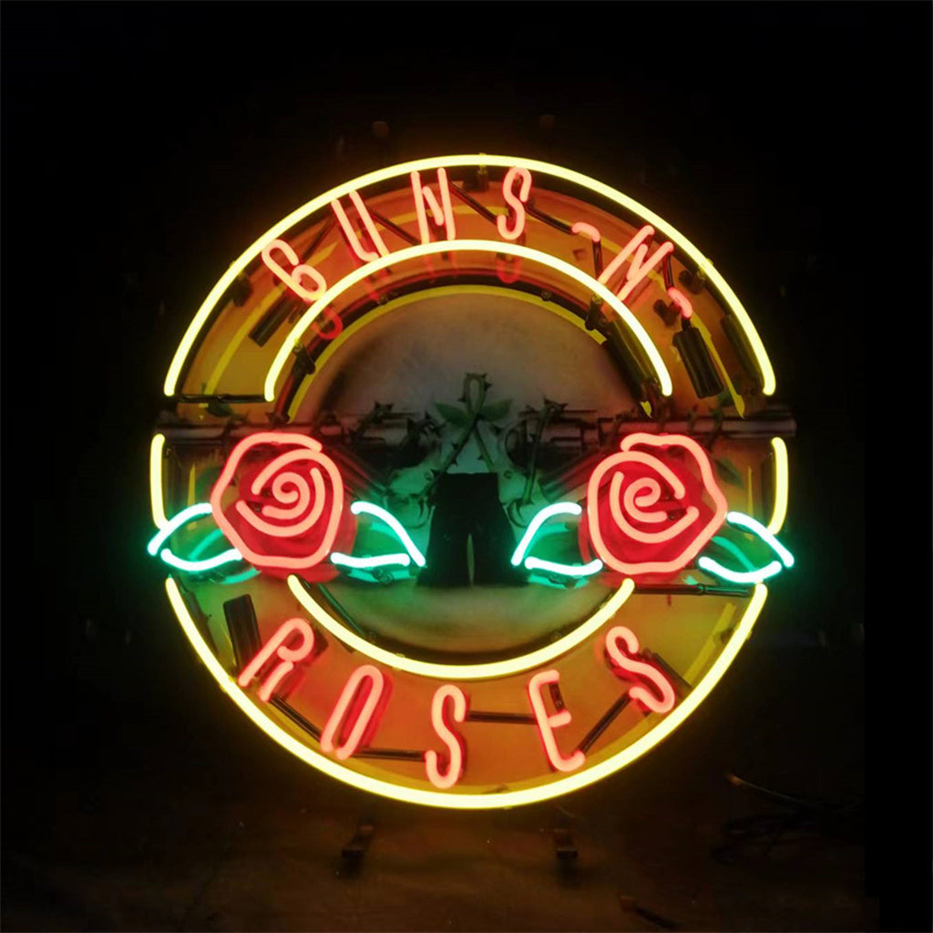 Circular neon sign with red 'Guns N Roses' letters, two red roses with green leaves inside a yellow ring, glowing against a dark background.