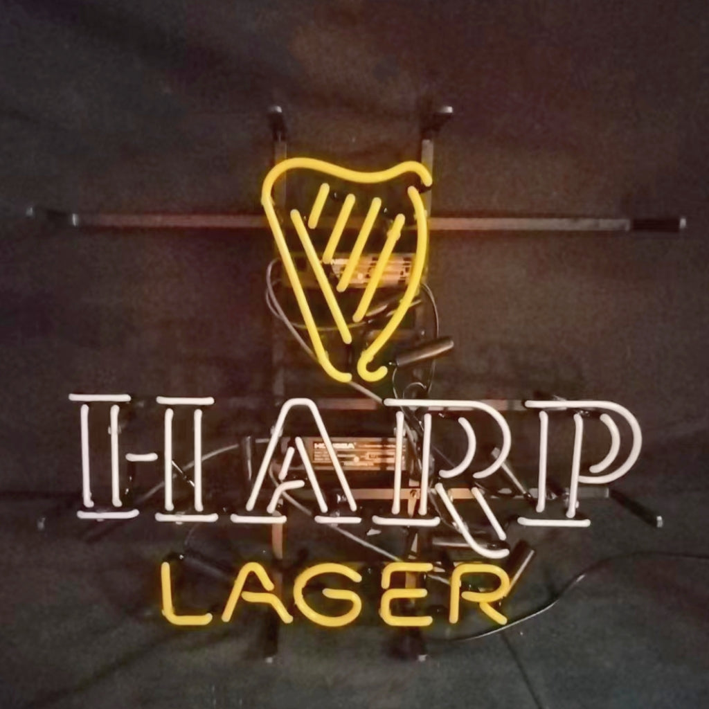 Neon sign with a yellow harp shape above white letters spelling H-A-R-P and yellow letters spelling L-A-G-E-R against a dark background.