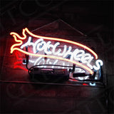 Neon sign displaying 'Hot Wheels' in white cursive letters with an orange flame outline above a brick wall, mounted with a black transformer box below.