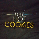 Neon sign with white steam lines above the word HOT in white neon and COOKIES in yellow neon against a dark background.