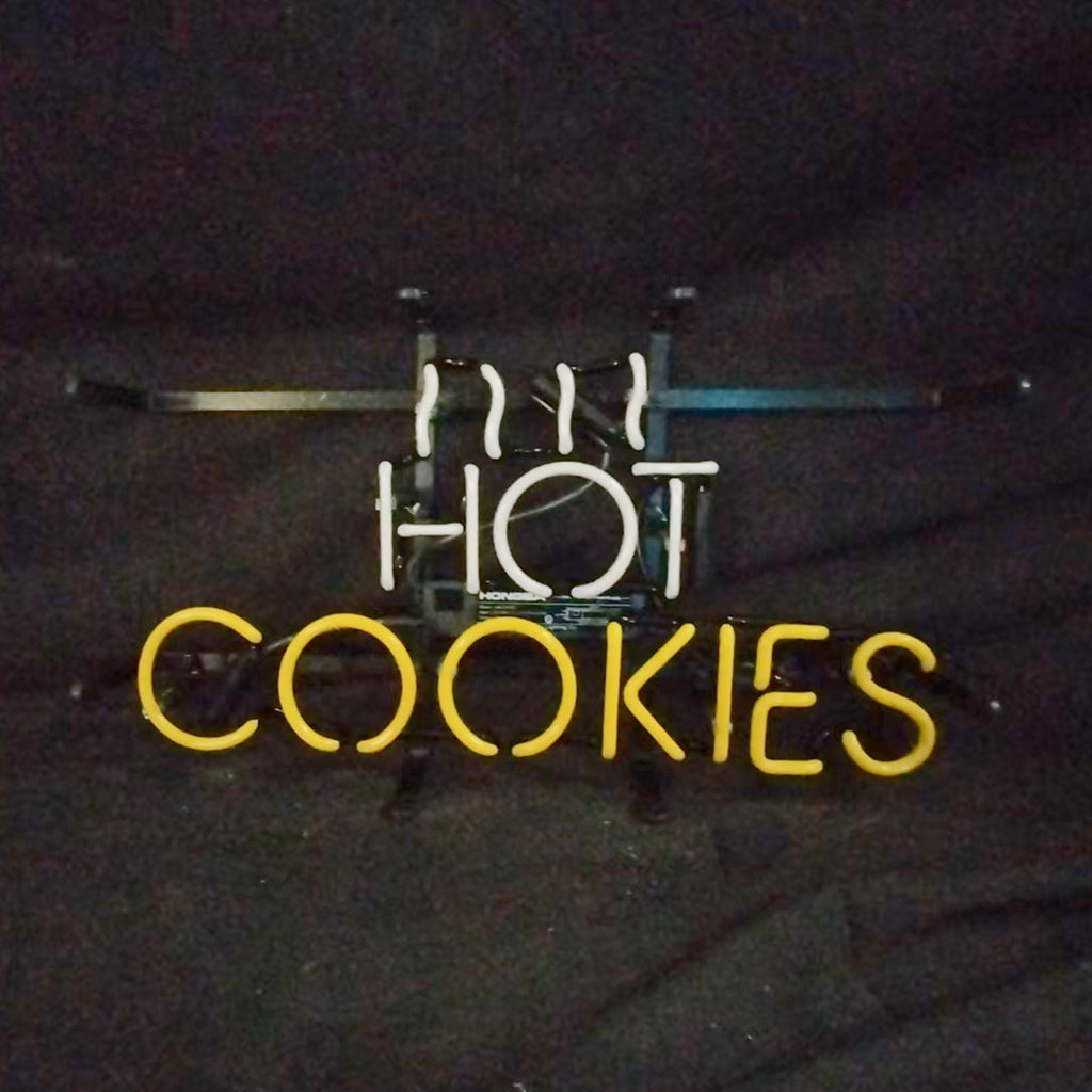 Neon sign with white steam lines above the word HOT in white neon and COOKIES in yellow neon against a dark background.