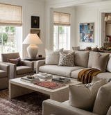 Neutral-toned living room with beige sectional sofa, various patterned throw pillows including charcoal ILU Pillow Cover by Susan Connor, and a textured beige armchair.