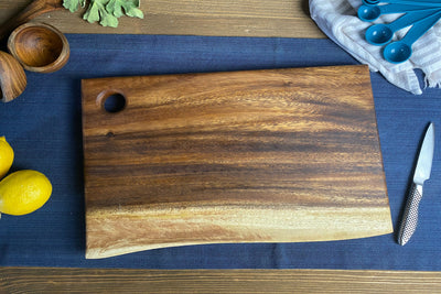 Medium live edge square end cutting board with hanging hole on a white background