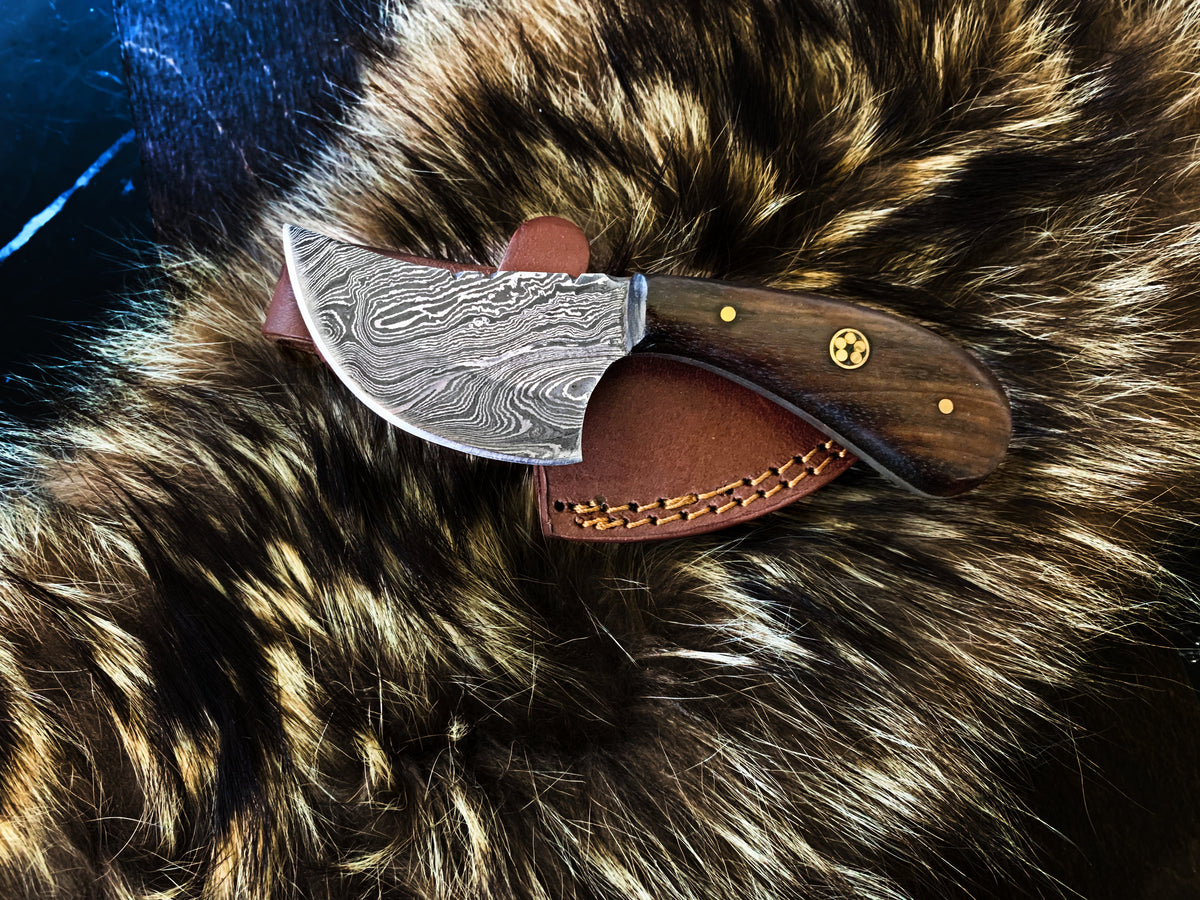 TD-090 fixed blade knife with Damascus steel blade and walnut handle resting on dark fabric