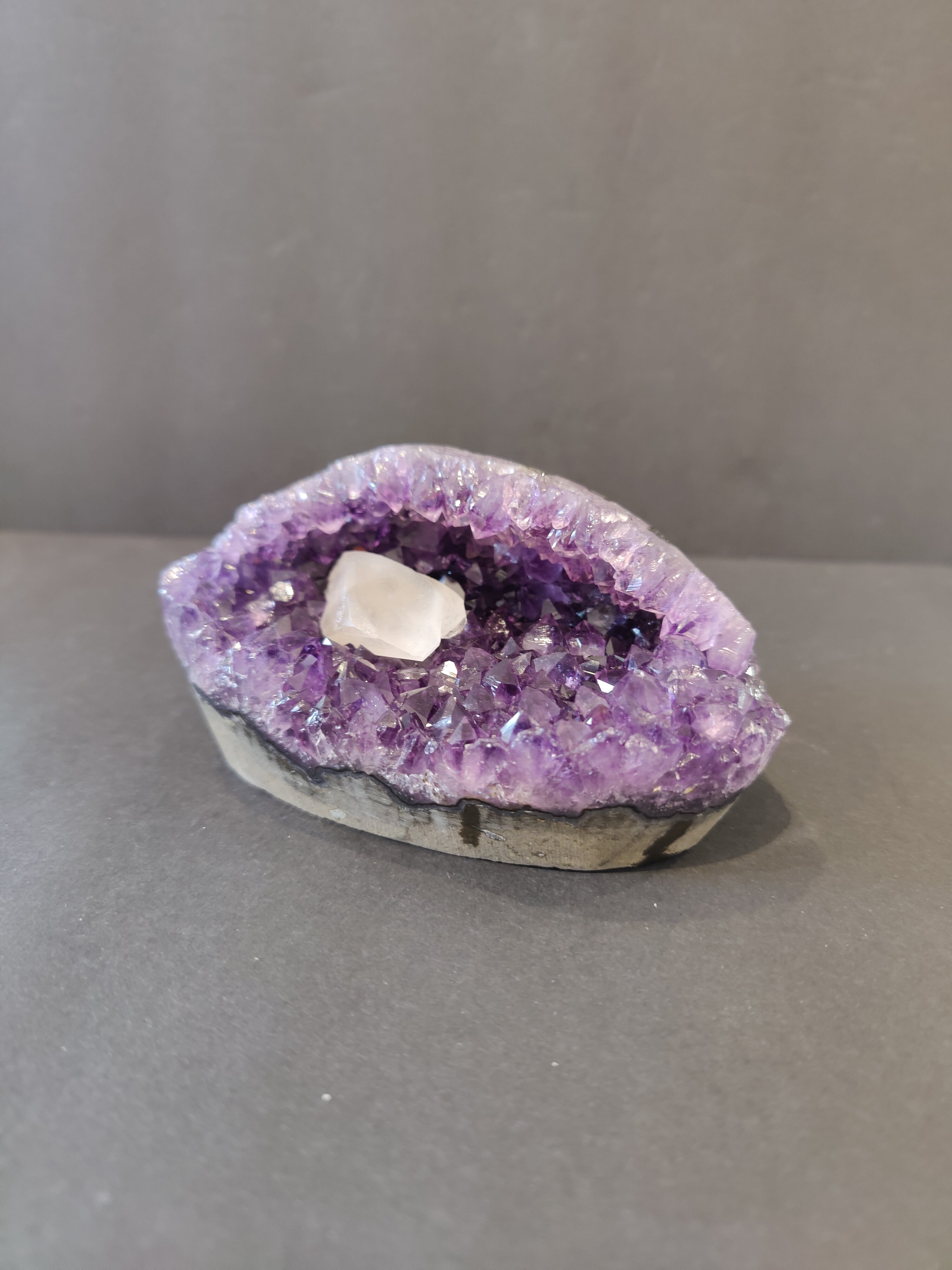 Polished Amethyst geode sculpture with Calcite crystal inclusions displayed upright