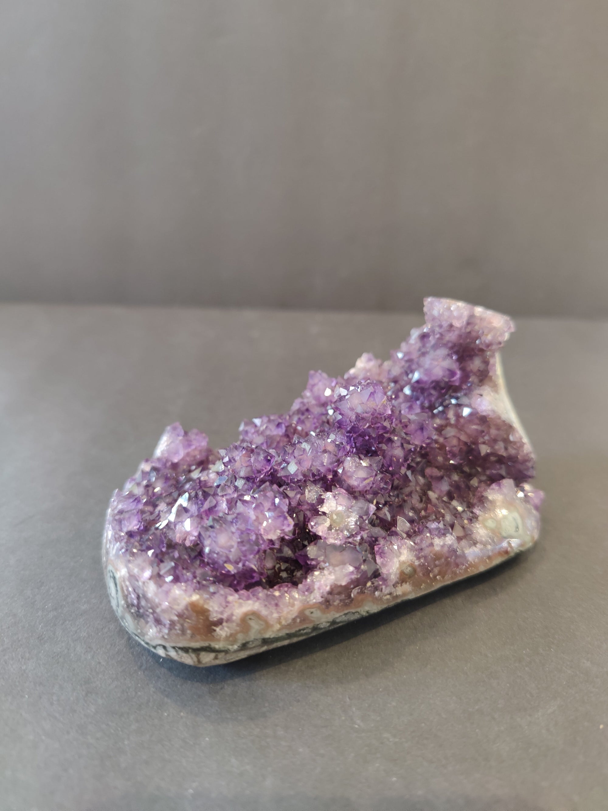 Polished amethyst geode sculpture with visible stalactite formations standing upright