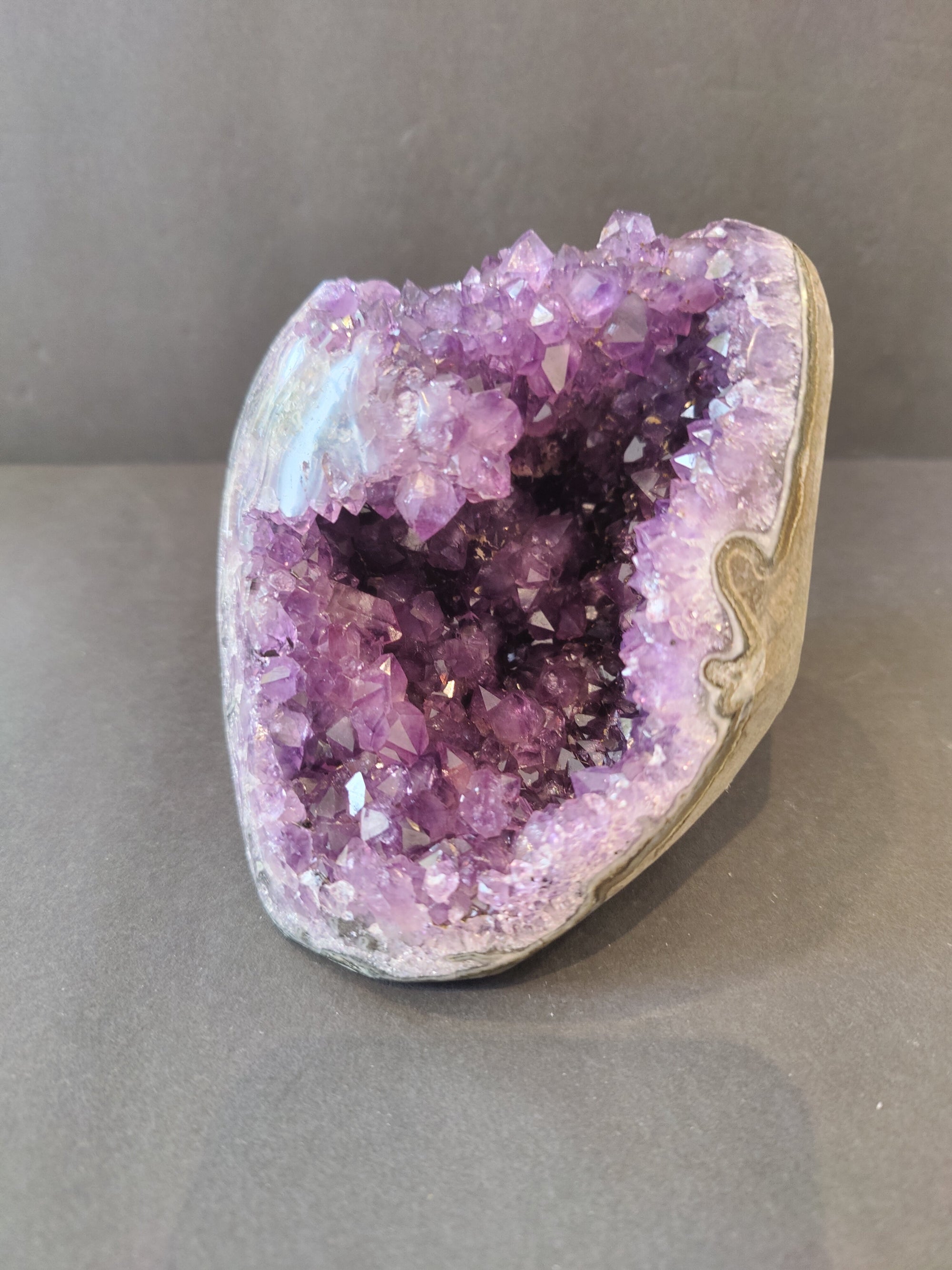 Polished amethyst geode with stalactite formation sculpture, showing deep purple crystals and rugged natural texture