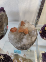 Polished clear quartz geode sculpture with visible quartz coated calcite inclusions against a dark background