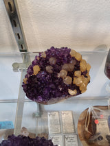 Polished amethyst geode sculpture with golden calcite crystal inclusions