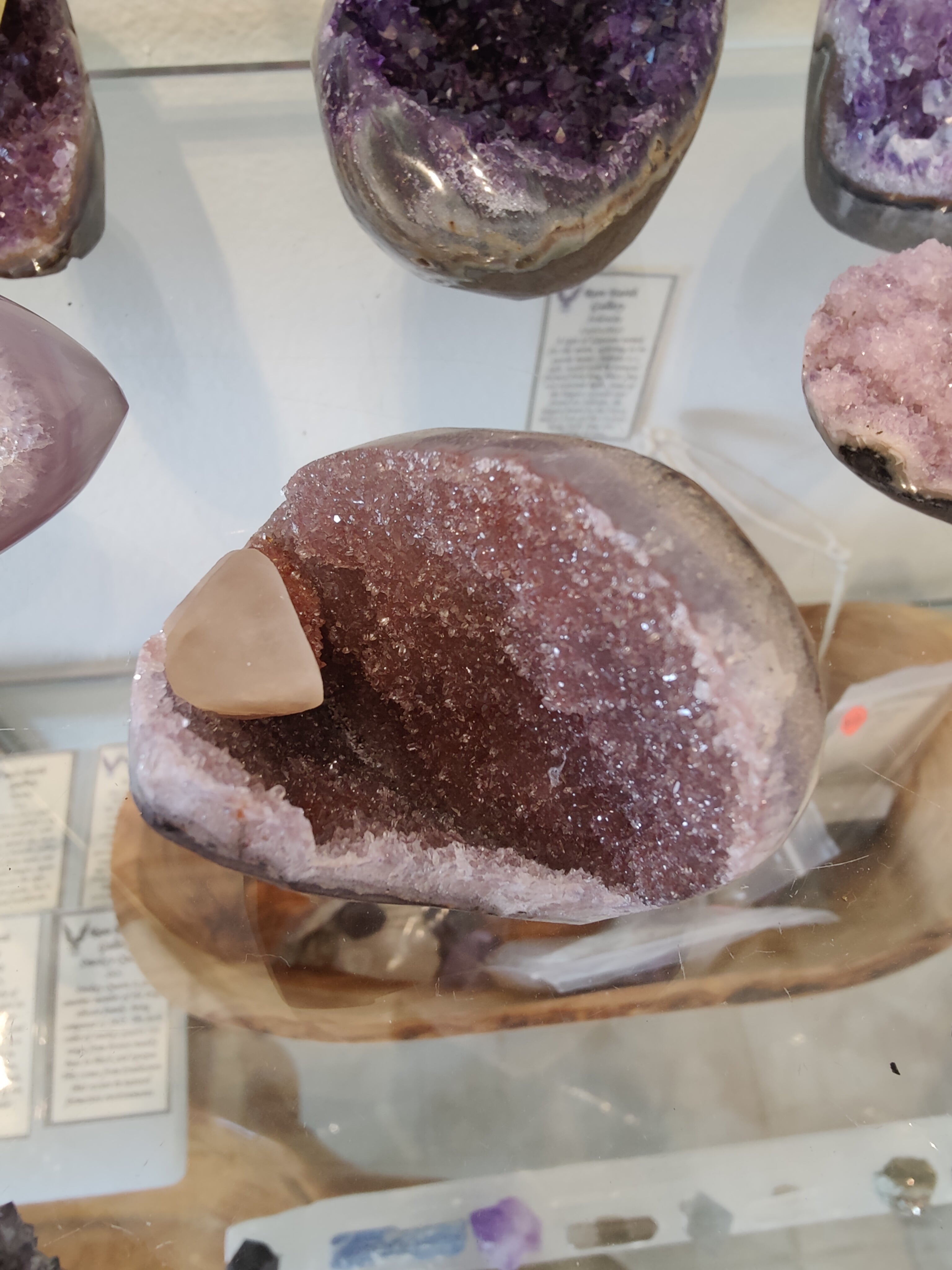 Polished Amethyst geode sculpture with visible Calcite crystal inclusions sitting on a dark surface