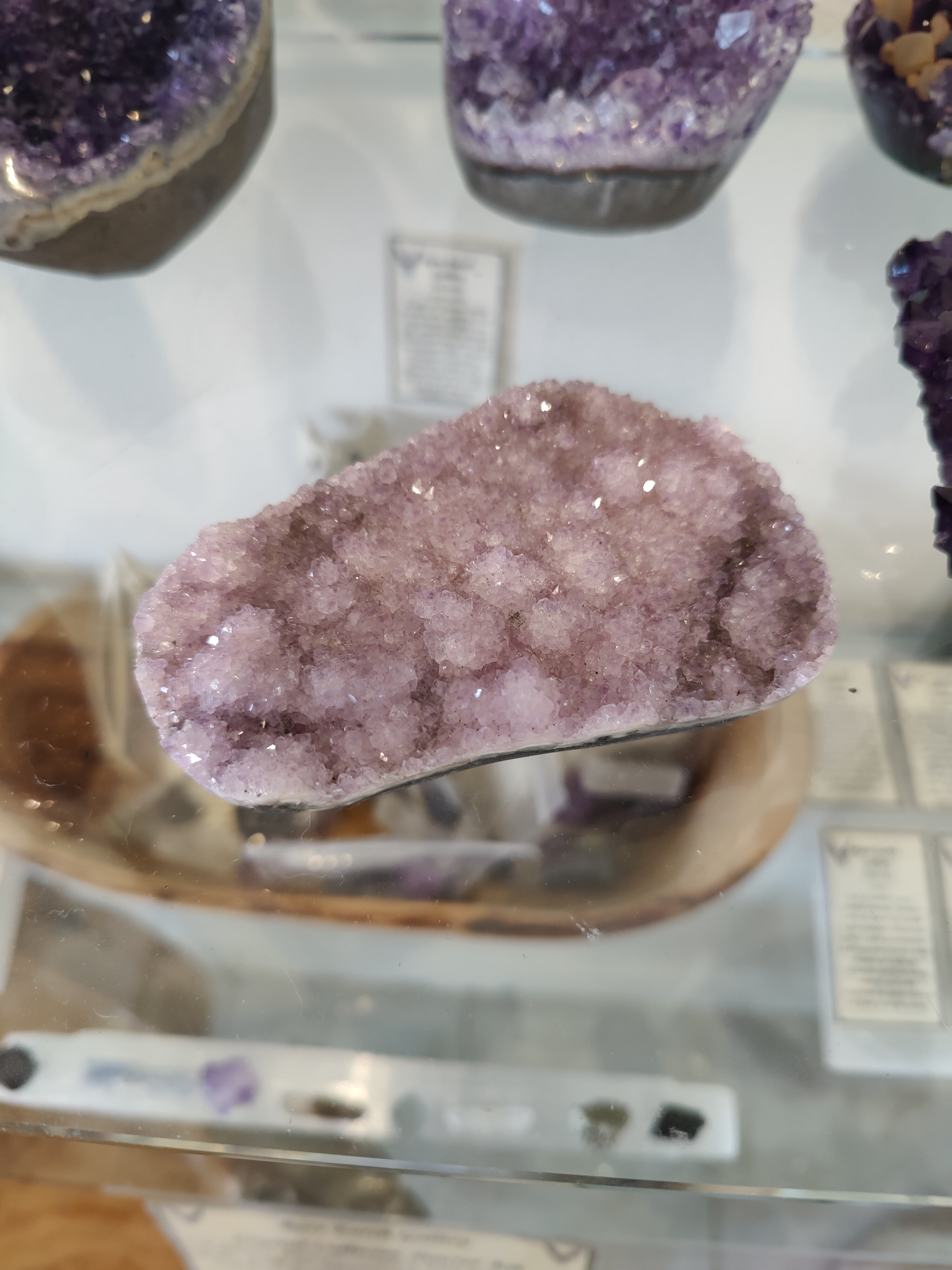 Polished edge Amethyst Druze Sculpture with purple crystalline surface resting on a white background