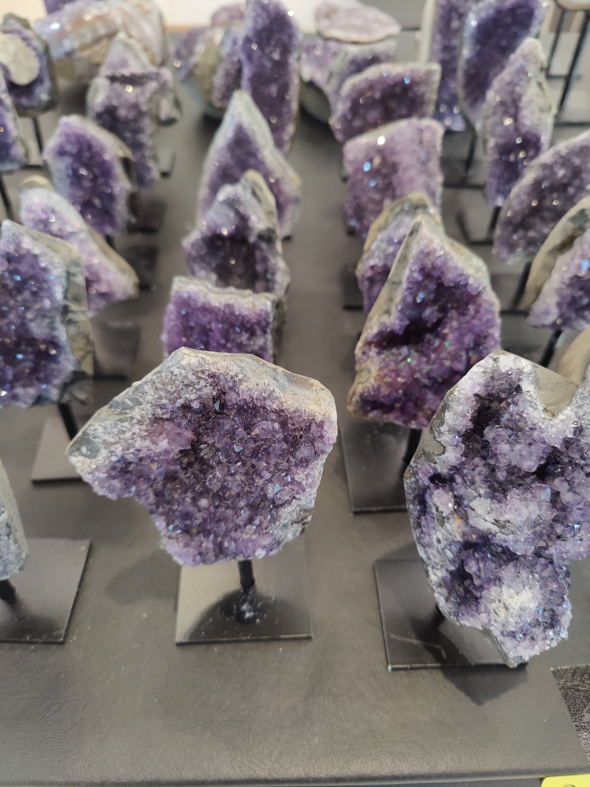 Amethyst geode on a metal stand with vibrant purple crystal interior and rough exterior.