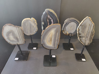 Agate slice displayed upright on a black metal stand with natural stone patterns in varied colors