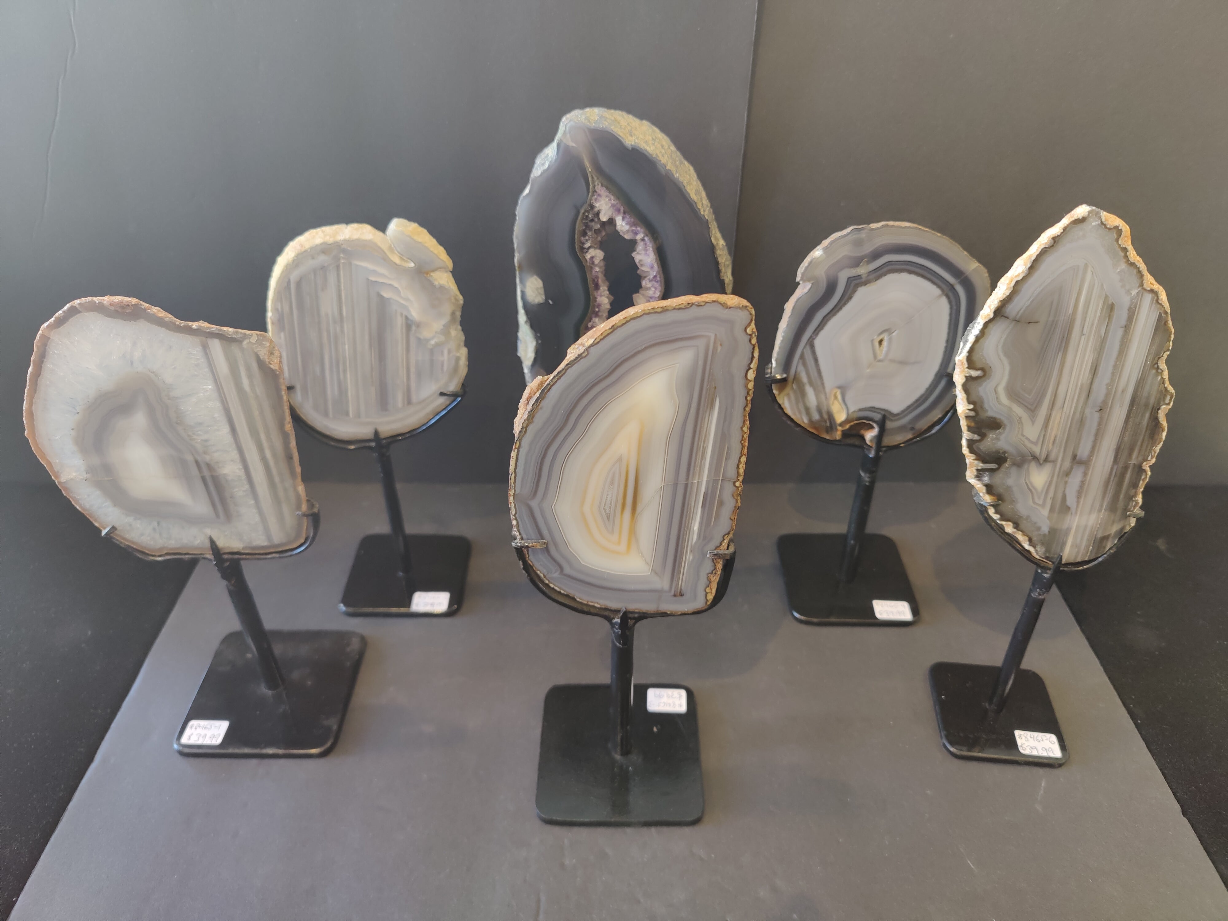 Agate slice displayed upright on a black metal stand with natural stone patterns in varied colors