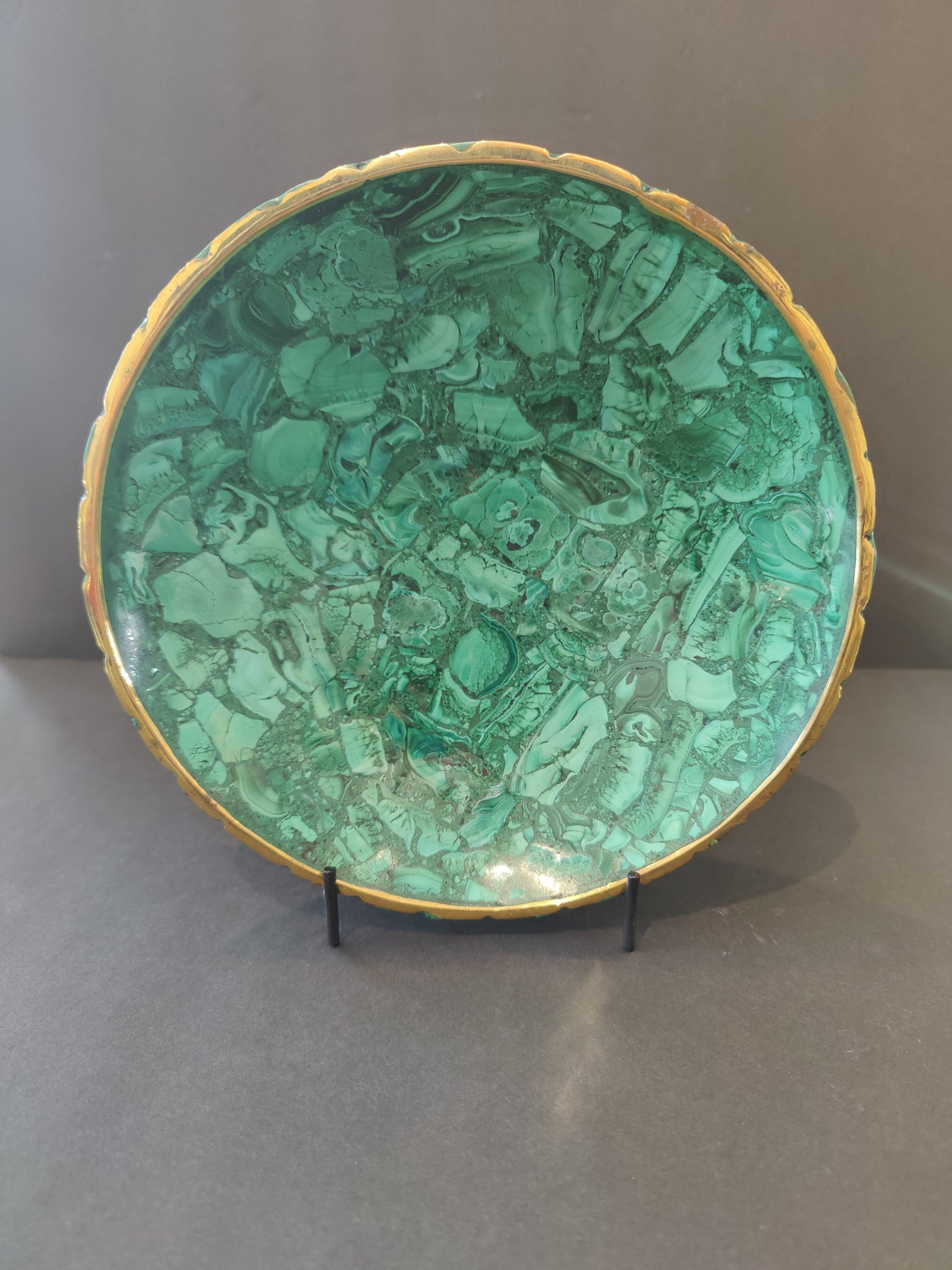 Malachite decorative bowl with gold rim shown on wooden surface