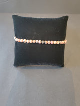 Delicate 4mm beaded stone bracelet with soft pink and gray hues displayed on a black cushioned stand against a gray background.