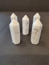Five white marble-patterned crystal towers with pointed tops arranged on a dark surface, featuring subtle gray veining unique to each piece.