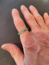 Close-up of a hand wearing a green 4mm beaded stone ring on the ring finger, set against a dark background.