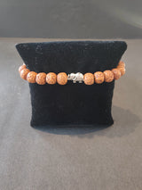 Bracelet of rudraksha seed beads with small silver elephant charms arranged on a white background