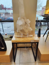 Onyx nesting table with a smooth beige stone top on black metal legs, displayed indoors against a window with parked cars visible outside.