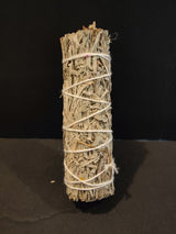 Compact bundle of dry sage leaves tightly wrapped with white string, standing vertically against a black background.