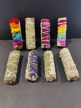 Assorted Sage Bundle Smudge Sticks with botanical elements laid out on surface