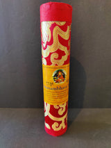 Cylindrical red and gold patterned container with a yellow label featuring a colorful Tibetan artwork, standing upright against a dark background.