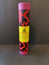 Tall cylindrical container wrapped in black fabric with red floral patterns and pink ends, featuring a yellow label with small text and a central icon.