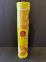 Tall cylindrical container wrapped in yellow fabric with intricate swirling patterns, featuring a yellow label with red deity image and Tibetan text, standing upright.