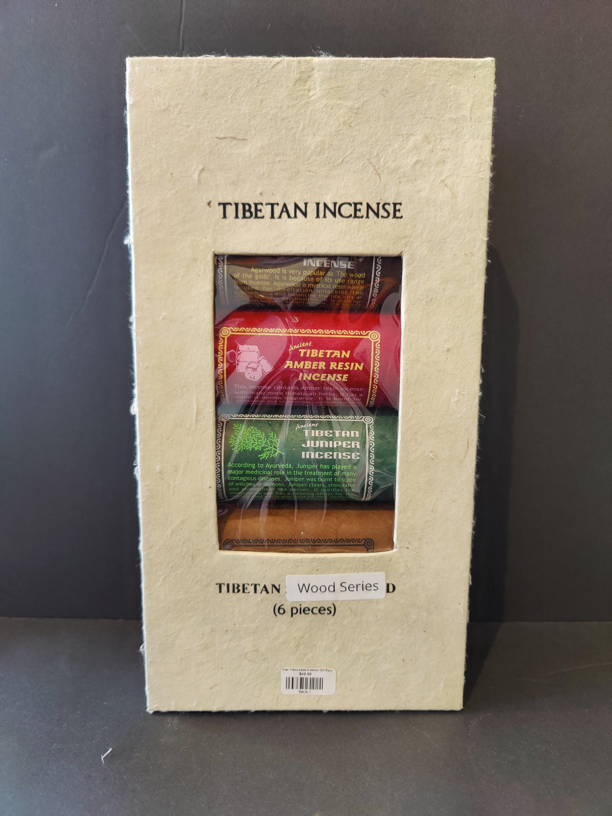 Rectangular beige package labeled 'Tibetan Incense' containing three visible colorful incense packs in red, green, and brown, shown against a dark background.