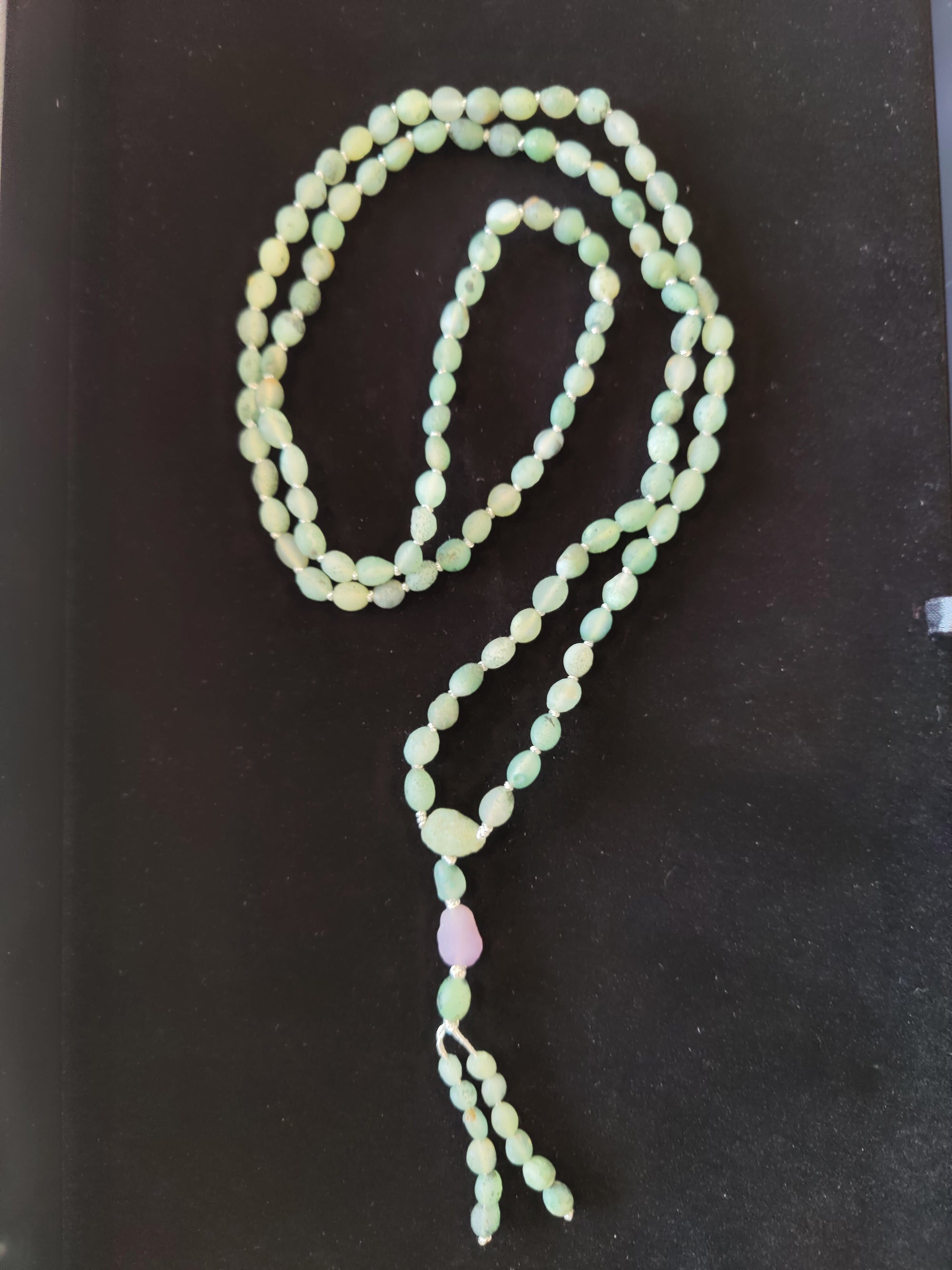 Gobi Desert Green Moss Agate with Amethyst Bead Mala Necklace laid flat showing green beads with a single purple bead