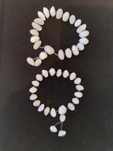 Two bracelets of white Gobi Desert agate beads, one larger with an extended bead cluster, both on a dark surface.