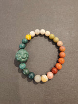 Stretch bracelet with polished round jasper beads in various colors from green to orange, featuring a carved green animal-shaped charm bead.