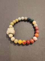 Multi-color jasper bead bracelet arranged in a circle with a carved animal charm bead, showcasing earthy tones of yellow, beige, green, and red on a gray background.