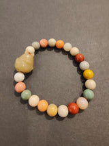 Round bead bracelet with multi-colored jasper stones in shades of green, orange, red, and white, featuring a cream-colored carved animal-shaped charm.