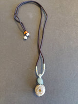 Pendant necklace with an agate stone resembling a spiral eye design, attached to a dark cord with two small beads near the clasp.