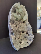 Vertical apophyllite cabinet specimen with pale green translucent crystals emerging from a white, crystalline geode base on a dark background.