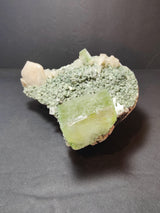 Green apophyllite cube and peach stilbite crystals clustered on a rough heulandite base against a dark background.