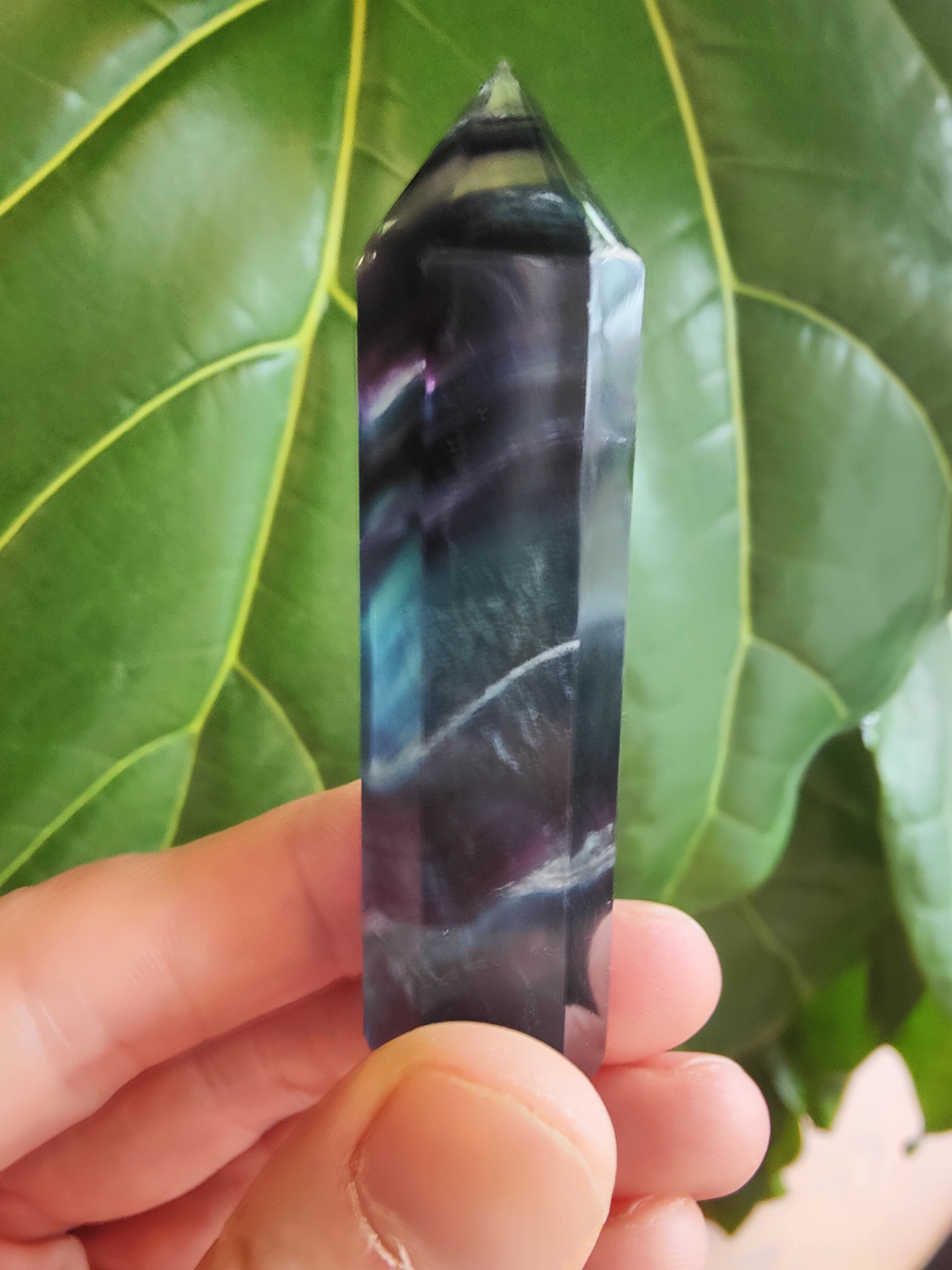 Polished multi-color fluorite tower about 3 inches tall with layered banding in purple, green, and clear shades